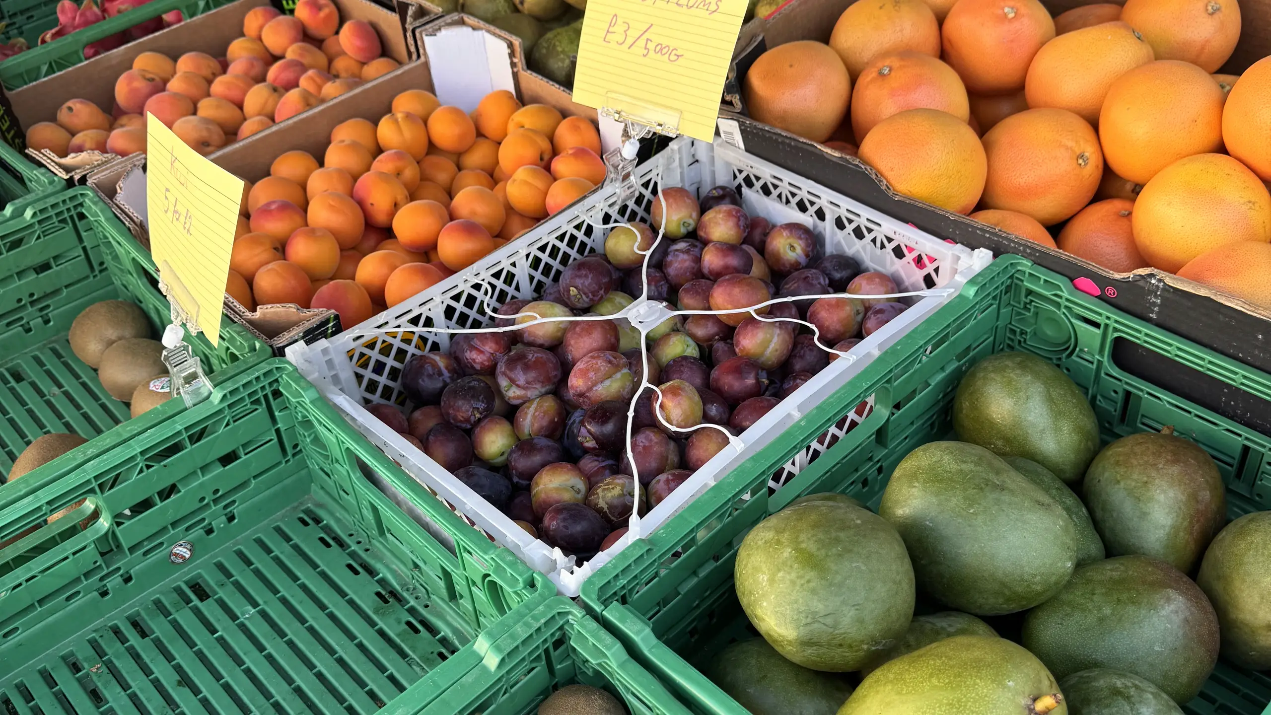 Crates of apricots, plums and mangoes on a fresh produce stall at Beccles Sunday Market