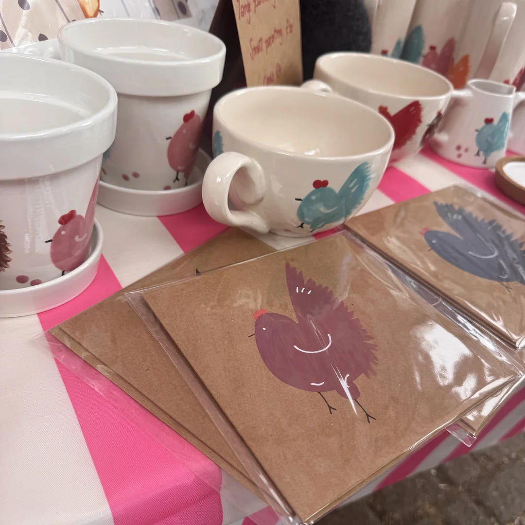 Hand-painted mugs and illustrated cards on a homeware stall at Beccles Sunday Market